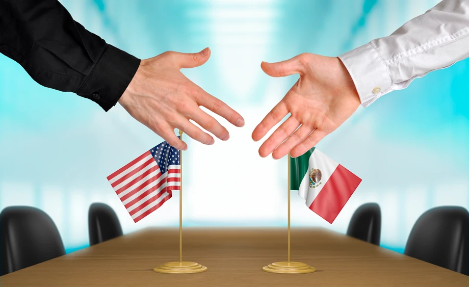 manos de hombre y de mujer sobre una mesa con banderas de méxico y usa