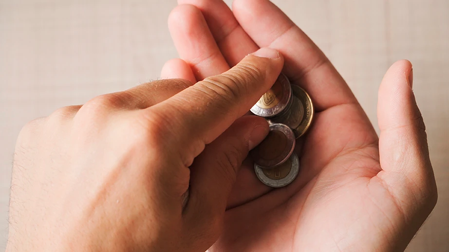 manos con monedas mexicanas